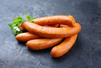Traditionelle rohe deutsche Bockwurst angeboten als close-up auf einem rustikalen schwarzen Board