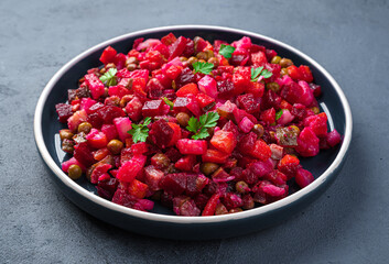Traditional salad vinaigrette with beetroot, vegetables, peas and fresh herbs on a dark background. Side view, close-up