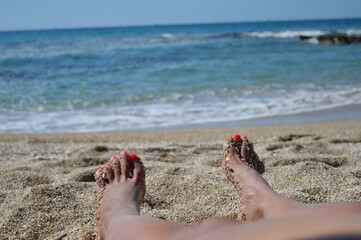 A young woman's foot covered with fine sand on the beach