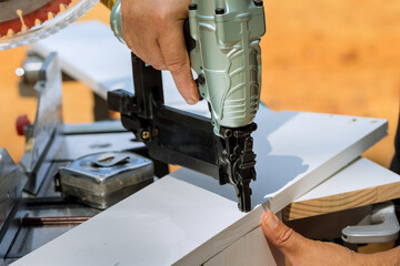 Assembling wood boards with nails with pneumatic air gun is done by carpenter