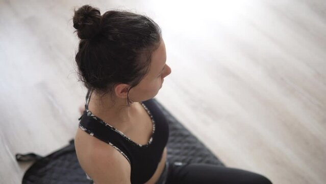 Young relaxed happy woman wearing sportswear and practicing yoga, doing revolved exercise, Parivrtta Sukhasana pose black at home