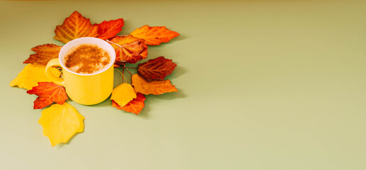 Autumn still life, yellow mug with of coffee or chocolate pastel background with bright leaves
