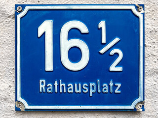 Blue enamel plate with the house number sixteen and half at the town hall square in the tourist...