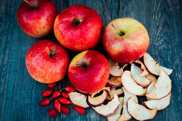 Apples, dried apples and rose hips lie on a dark wooden table Autumn