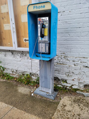 Outdoor pay phone with a cord by an old brick building - obrazy, fototapety, plakaty
