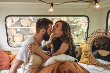 Young beautiful loving couple travelling across country in the van. Millennial man and woman in a travel camper. Cozy atmosphere, vacations vibe