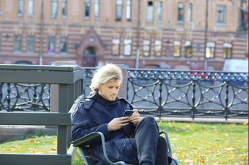 Lifestyle portrait of a young man using a smart phone outdoors. man relaxing in autumn park