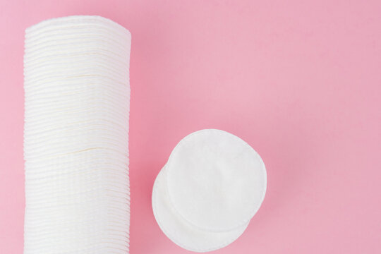 Cotton pads on pink background, top view.