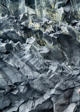 Swirling natural stone formation textural backdrop. Dramatic gray basalt rock. Vertical rock background.