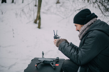 Aerial photography specialist with a copter in his hands on the street in winter. A male aerial drone operator at work on a film set for a movie