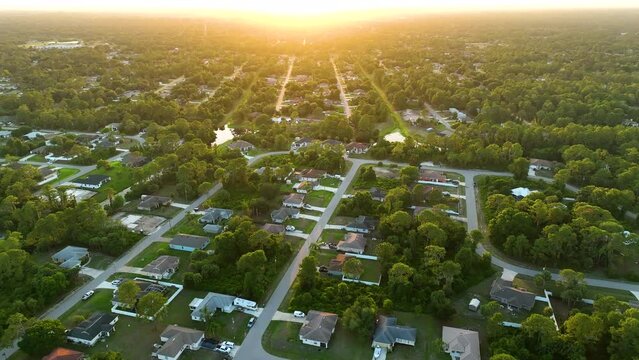 Aerial landscape view of suburban private houses between green palm trees in Florida quiet rural area at sunset