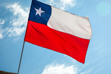 Fototapeta na wymiar National flag of Chile blowing on blue sky in Santiago, South America