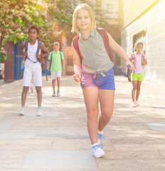 Schoolgirl with backpack walking down the street to school
