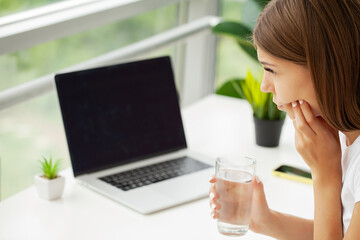 Disillusioned lady feeling pain in tooth while working in office.