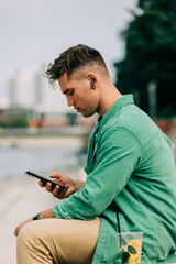 Obraz premium Stylish guy with earphones listen music and sit on city street in Wroclaw, Poland