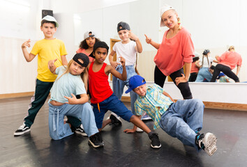 Group portrait of happy preteen hip hop dancers with female choreographer in modern dance studio