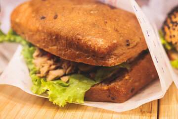 Beautifully decorated catering banquet table on event with different food snacks and appetizers setting with bagel and sandwiches, triange, baguette club submarine sandwich, on a wooden plate