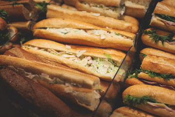 Beautifully decorated catering banquet table on event with different food snacks and appetizers setting with bagel and sandwiches, triange, baguette club submarine sandwich, on a wooden plate