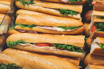 Beautifully decorated catering banquet table on event with different food snacks and appetizers setting with bagel and sandwiches, triange, baguette club submarine sandwich, on a wooden plate