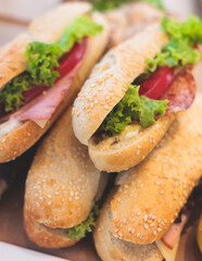 Beautifully decorated catering banquet table on event with different food snacks and appetizers setting with bagel and sandwiches, triange, baguette club submarine sandwich, on a wooden plate