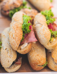 Beautifully decorated catering banquet table on event with different food snacks and appetizers setting with bagel and sandwiches, triange, baguette club submarine sandwich, on a wooden plate
