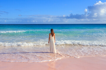 Woman walking on Horseshoe Bay Beach in Bermuda, famous for its pink sand
