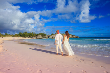 Couple walking on the Horseshoe Bay Beach in Bermuda, famous for its pink sand