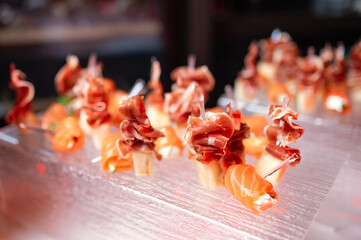 a lot of canapes with jamon and cheese on a transparent plate