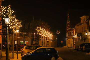 Plakat Christmas illumination in Germany. half timbered houses and festive decorations.Christmas in Europe.Decorative yellow flashlight and shimmering garland on a black background. 