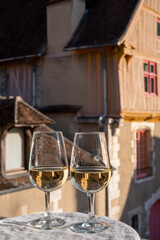 Tasting of white grand cru classe chablis wine with old French houses on background, Burgundy, France