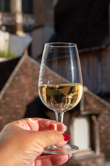 Tasting of white grand cru classe chablis wine with old French houses on background, Burgundy, France