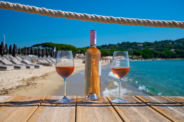 Glasses and bottle of cold rose wine from Provence served outdoor on wooden yacht pier with view on...