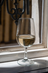 Tasting of white grand cru classe chablis wine with old French houses on background, Burgundy, France