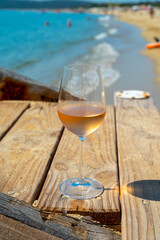Glasses of cold rose wine from Provence served outdoor on wooden yacht pier with view on blue water and white sandy beach Plage de Pampelonne near Saint-Tropez, France