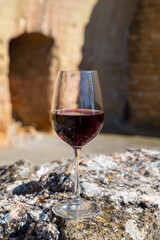 Glass of red dry wine and ruins of medieval castle of Châteauneuf-du-Pape ancient wine making village in France