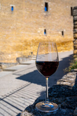 Glass of red dry wine and ruins of medieval castle of Châteauneuf-du-Pape ancient wine making village in France