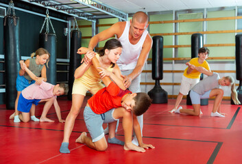 Coach teaches children to apply self-defense techniques in the gym