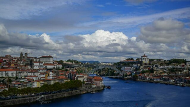 Timelapse of motorboats driving on River Douro with Luis I Bridge spanning shores under cludy sky
