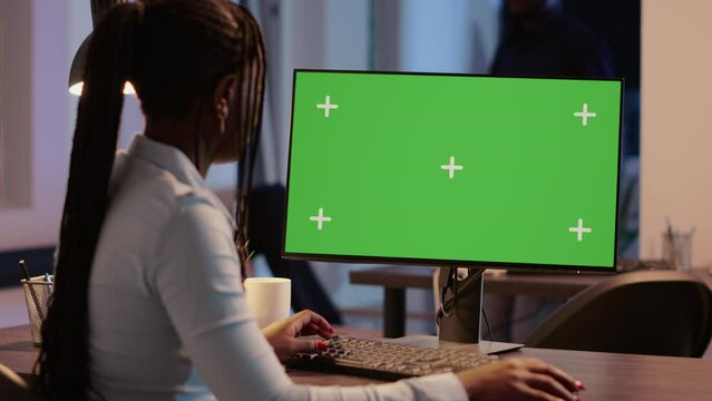 Company worker analyzing greenscreen display on monitor, looking at isolated screen in business office. Using blank copyspace template with mockup background and chroma key. Tripod shot.