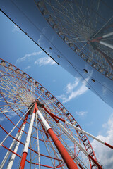 Beautiful large Ferris wheel near building against blue sky, low angle view