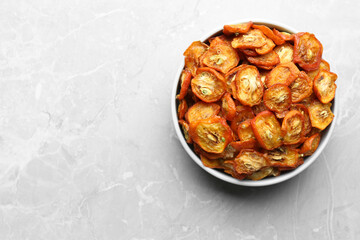 Bowl with cut dried kumquat fruits on white marble table, top view. Space for text