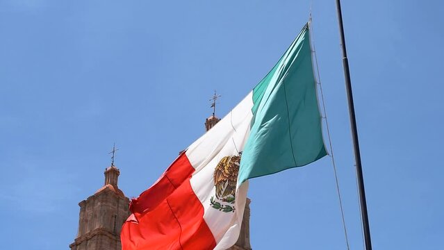 Mexican flag waving with Parroquia Cathedral Dolores Hidalgo Mexico, Cradle of National Independence Where Father Miguel Hidalgo made his Grito starting the 1810 War of Independence in Mexico