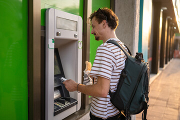 side view man use ATM machine to withdraw money with credit card