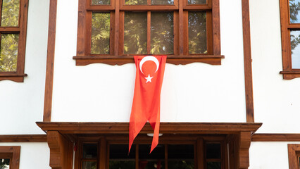 Turkish flag hanging on the window of a Traditional Turkish house. Celebrating 29 October or 23 April, 30 August. Turkish National holiday concept