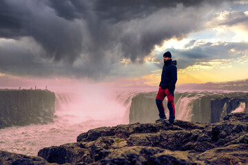 adventurous man on mountain between waterfalls under a storm