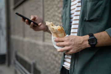 man caucasian tourist young adult eat sandwich and use mobile phone