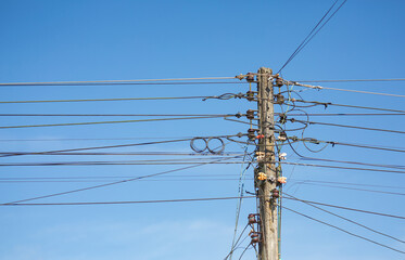 Concrete power poles have relatively unorganized electrical wiring.