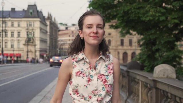 Girl walking in street of Prague city, turning and looking into camera, face or head closeup view