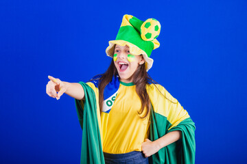 young girl, soccer fan from Brazil. dressed in hat and flag. pointing at something far away.