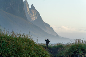 hiking in the mountains at sunset with photographic model. Black sand beach with vegetation